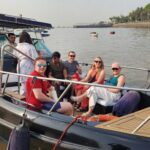 Tourists enjoying a luxury speedboat ride in Mumbai harbor near the Gateway of India.