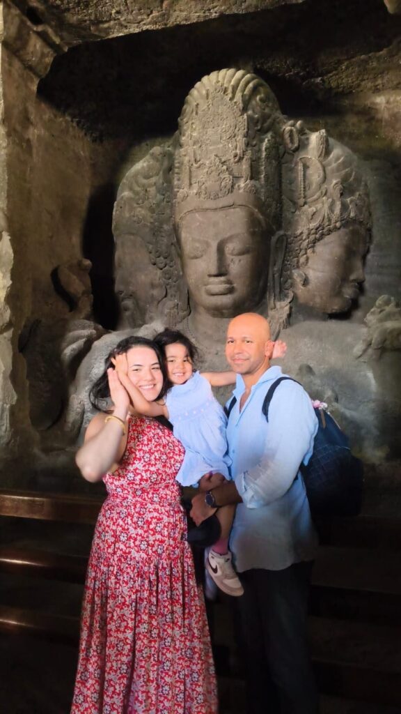 Family posing in front of the Trimurti Shiva sculpture at Elephanta Caves on a private speedboat tour