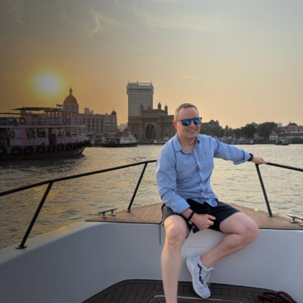 Traveller enjoying a private yacht cruise in Mumbai with the Gateway of India in the background at sunset.